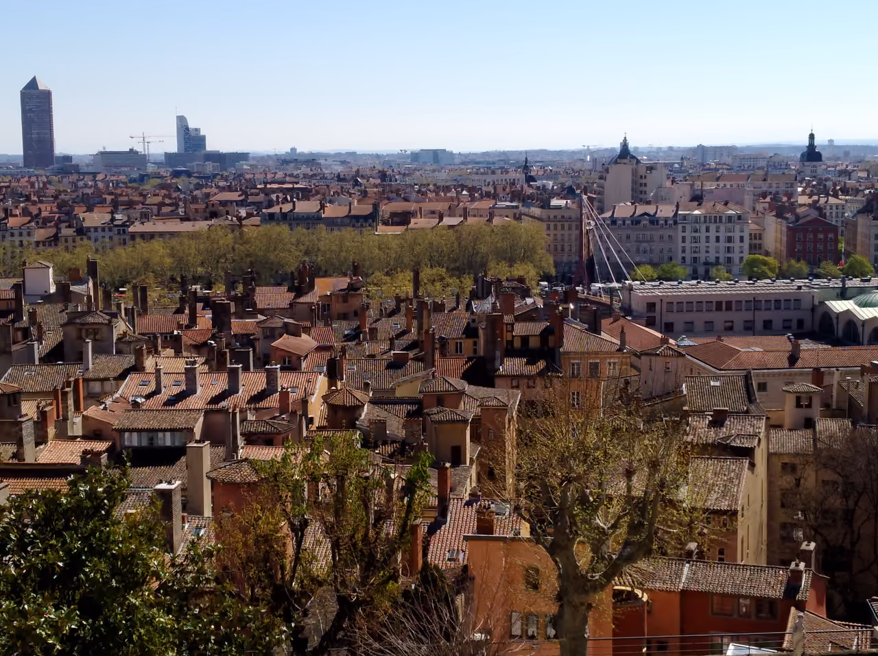 Panoramic view over traditional tiled rooftops and chimneys towards modern city skyscrapers