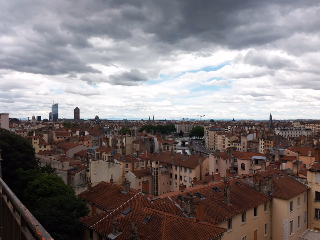 Panoramic view of the city centre of Lyon with traditional rooftops and modern skyscrapers under a cloudy sky