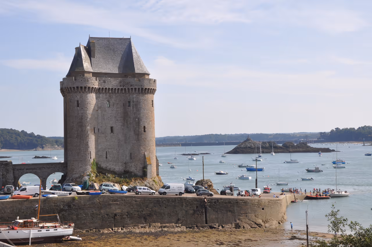 Medieval stone Solidor Tower on the coast overlooking small boats anchored in the emerald waters of the Rance estuary in Saint-Malo
