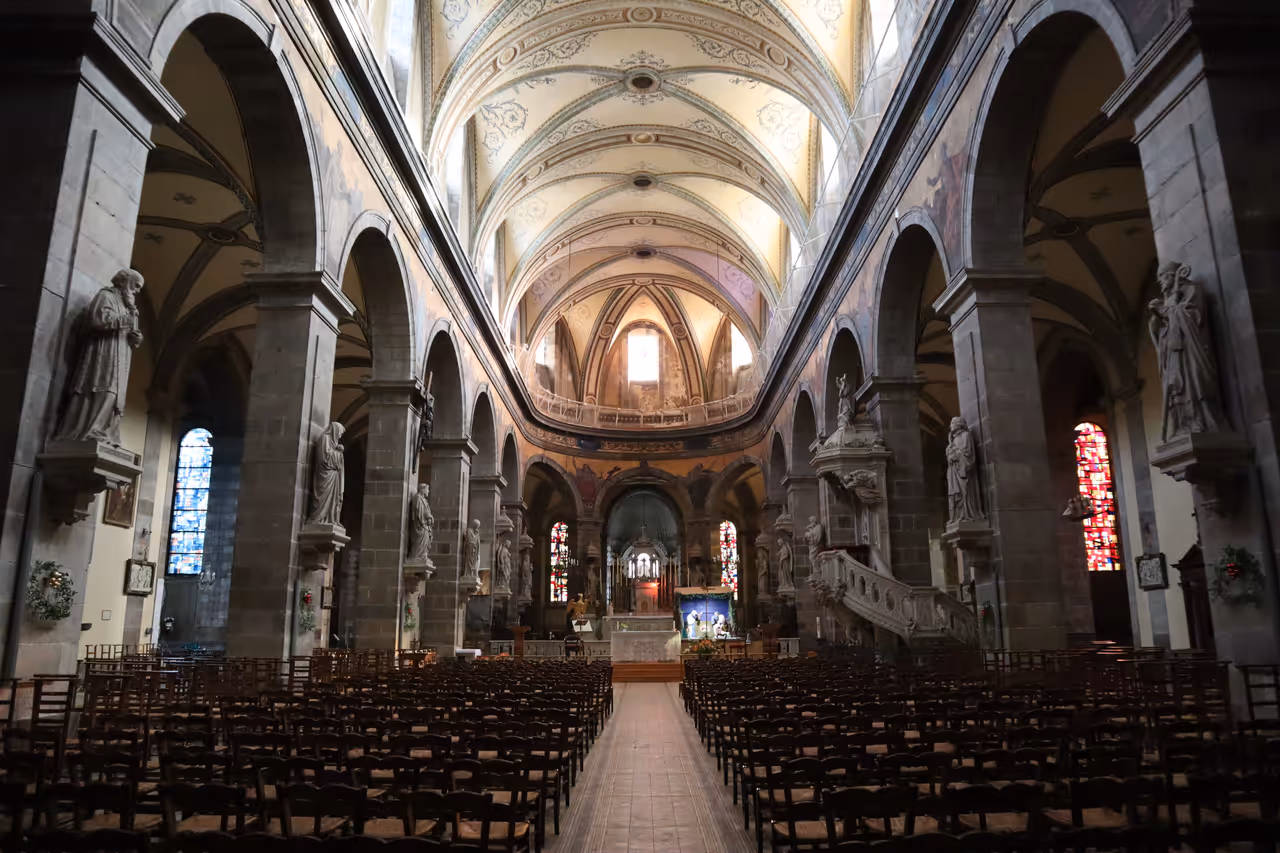 Interior view of the Église Sainte-Croix de Saint-Servan in Saint-Malo featuring stone columns, arched vaulting, and stained glass windows