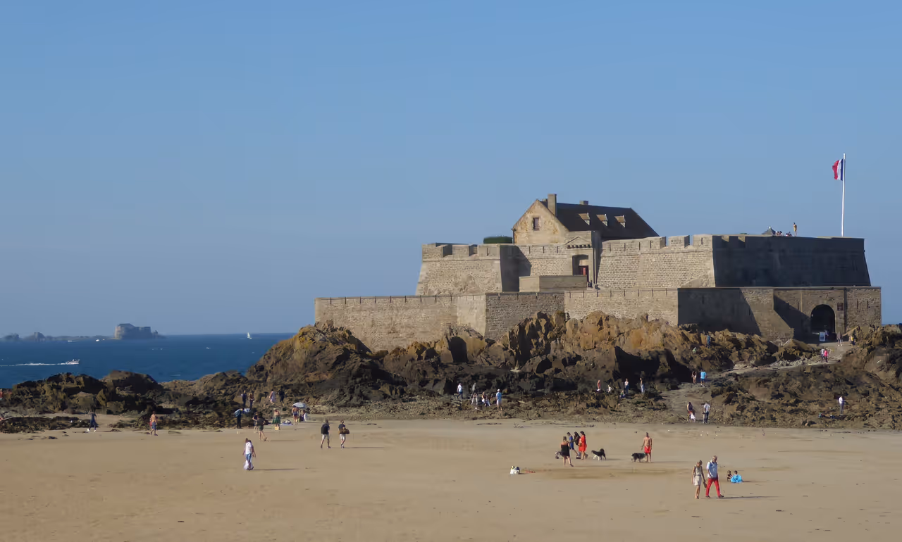 View of Éventail Beach at low tide, with Fort National and in the distance La Conchée.