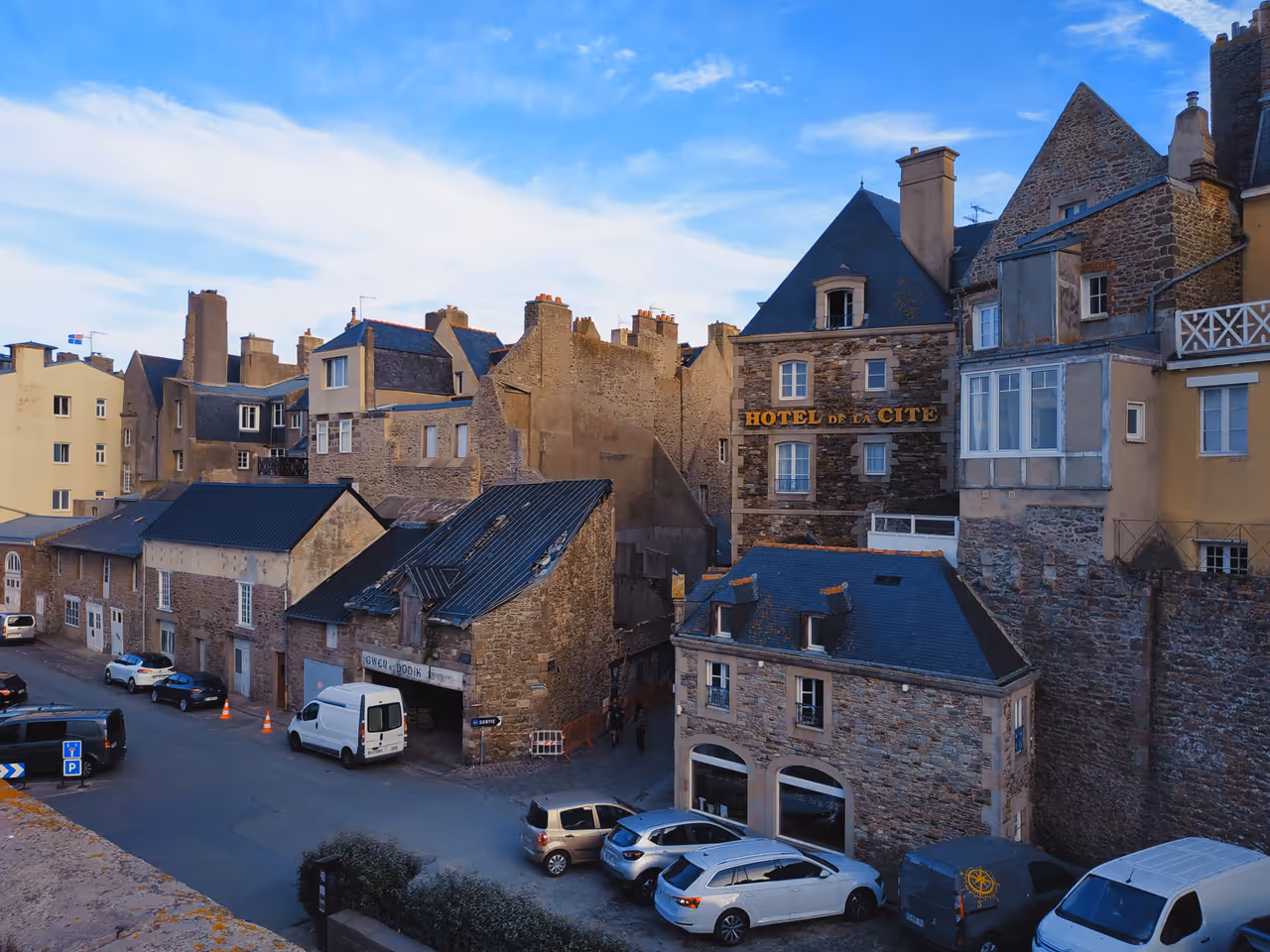 Narrow cobblestone street in the intra-muros old town of Saint-Malo with historic stone buildings and a view of Hotel de la Cité