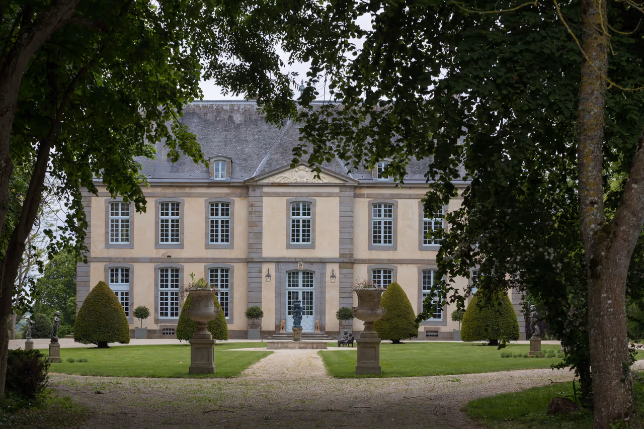 Symmetrical stone façade and formal manicured gardens of the historic Malouinière du Bosc manor in Saint-Malo