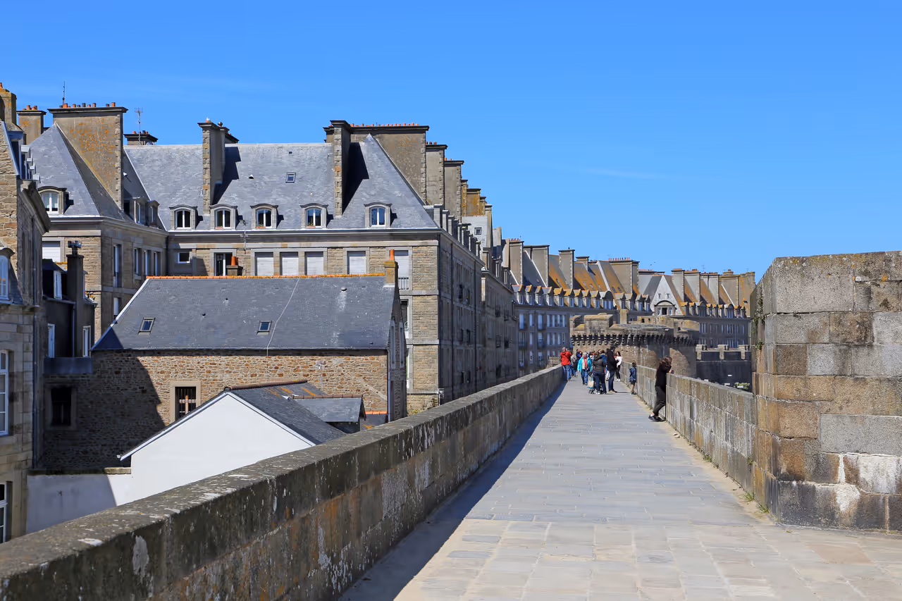 Stone ramparts of the fortified city of Saint-Malo with historic granite buildings under a clear blue sky