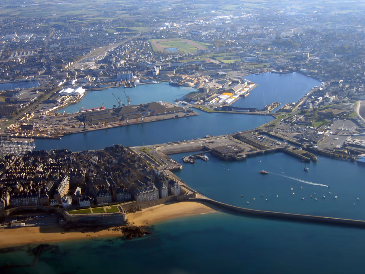 Aerial overview of the historic walled city and port of Saint-Malo with its stone ramparts, harbor basins, and coastal fortifications
