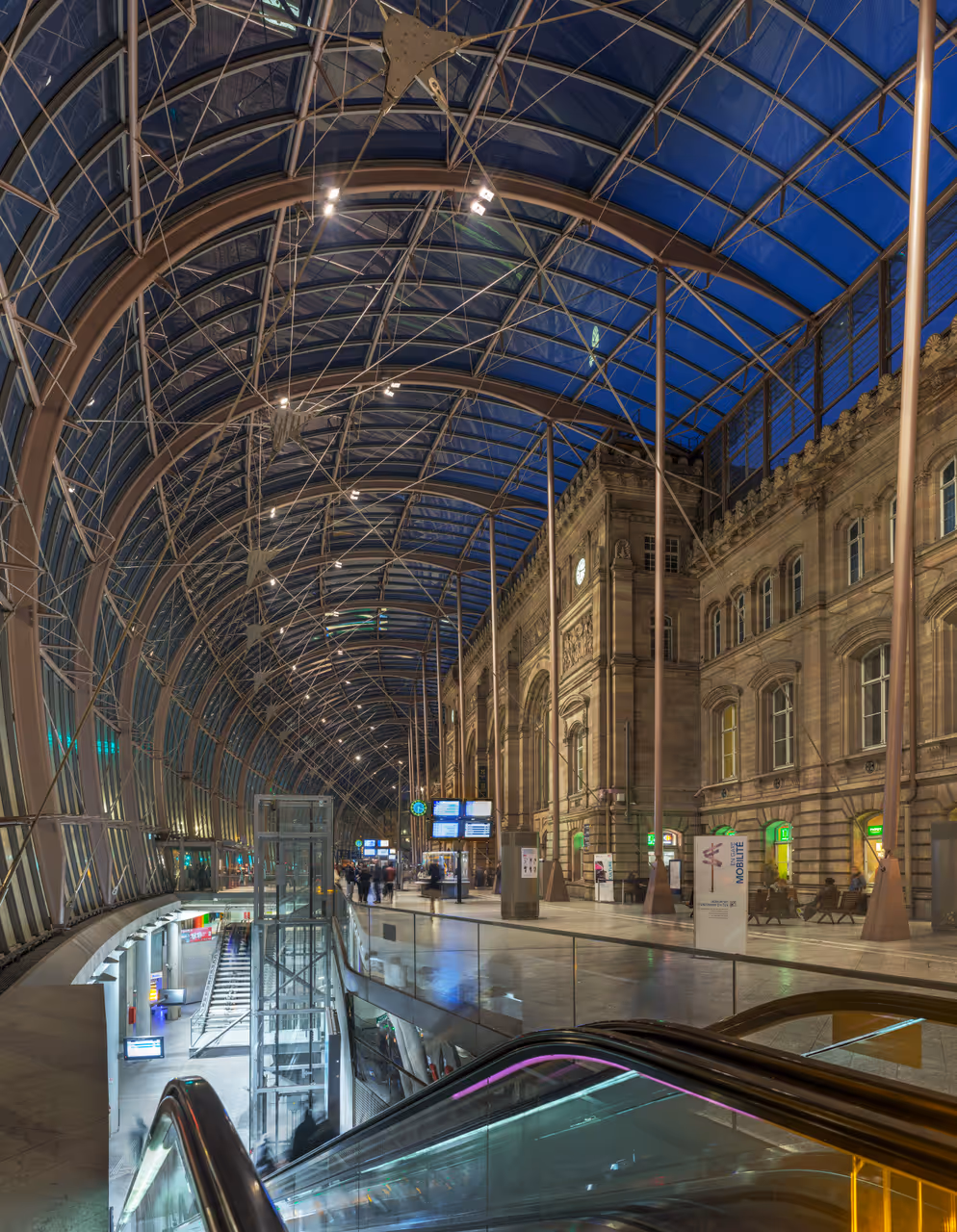 The interior of Gare de Strasbourg, showing the façade and the modern glass roof creating an entrance hall