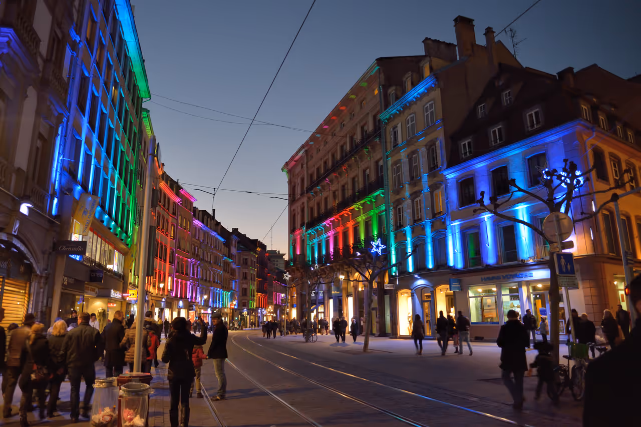 People on an empty street, with illuminated buildings