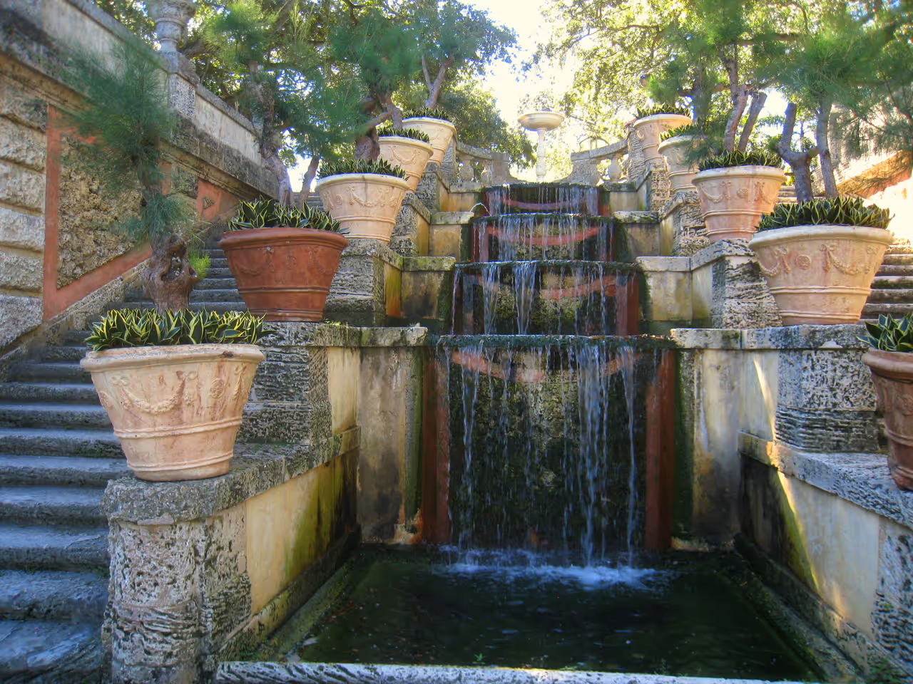 Multi-tiered cascading water stair fountain with stone steps and large terracotta planters in the Italian Renaissance style formal gardens of Villa Vizcaya