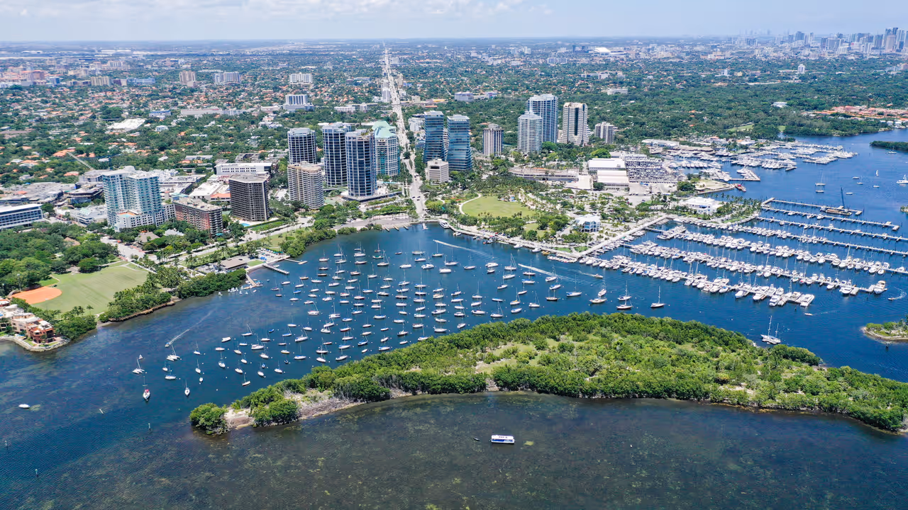 Aerial view of Downtown Coconut Grove marina with yachts moored in the harbour, Coral Way in the background, and the Brickell skyline on the far right