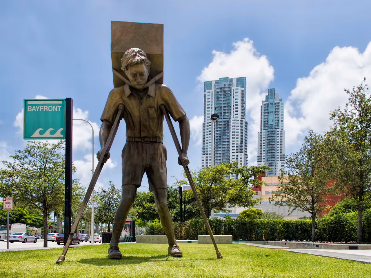 Bronze sculpture The Tower of Snow by Enrique Martínez Celaya featuring a boy on crutches outside the Freedom Tower in Miami