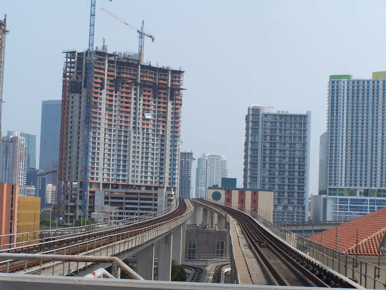 Elevated rapid transit tracks curving through a cityscape with skyscrapers and buildings under construction in Miami, Florida