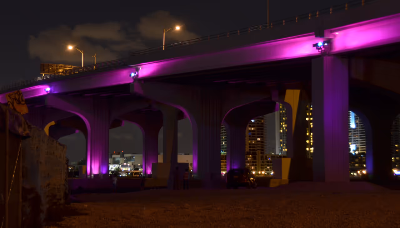 MacArthur Causeway bridge illuminated with vibrant purple lights at night in Miami