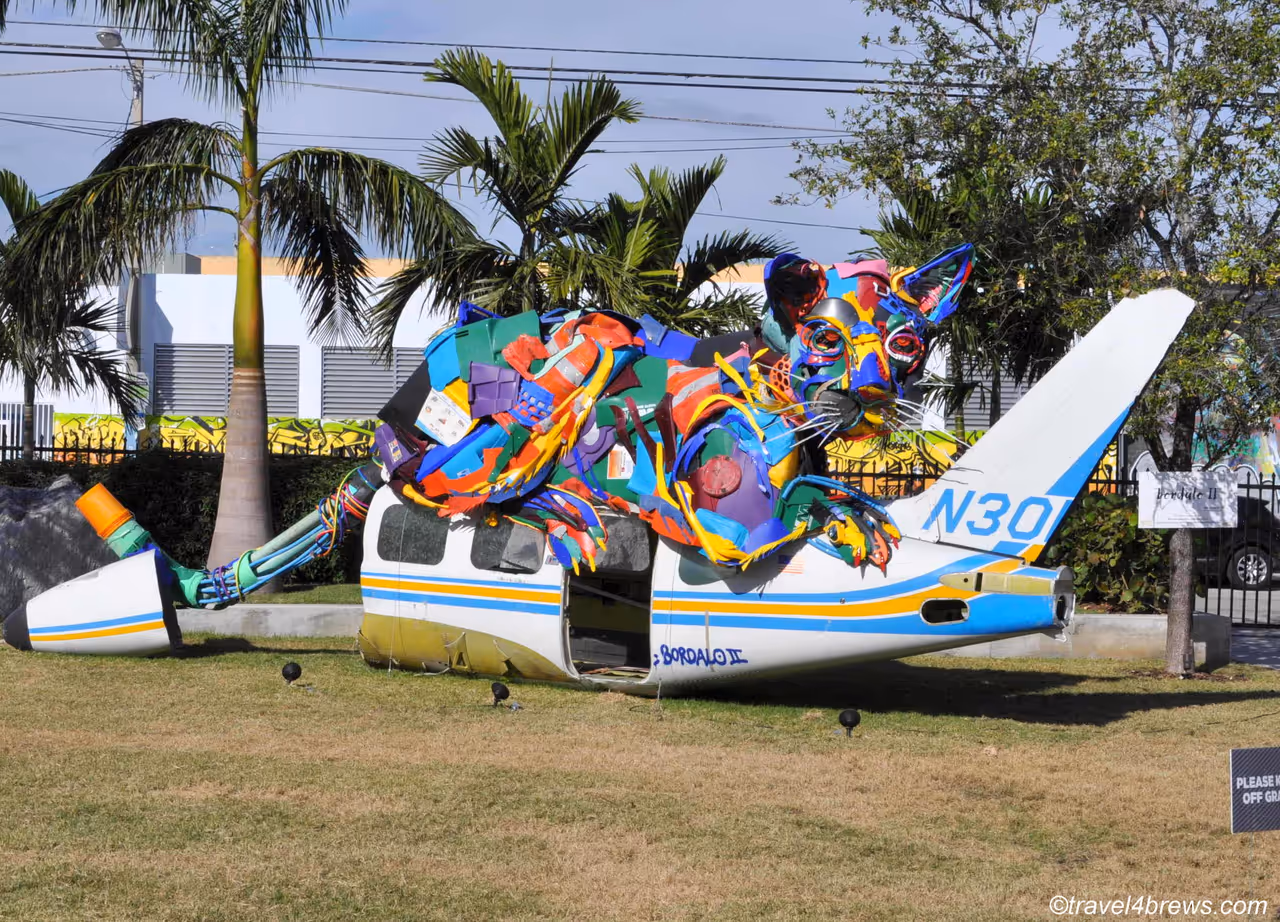 A colourful street art sculpture of an animal created from recycled plastic trash and debris, built into a crashed aeroplane fuselage in the Wynwood art district