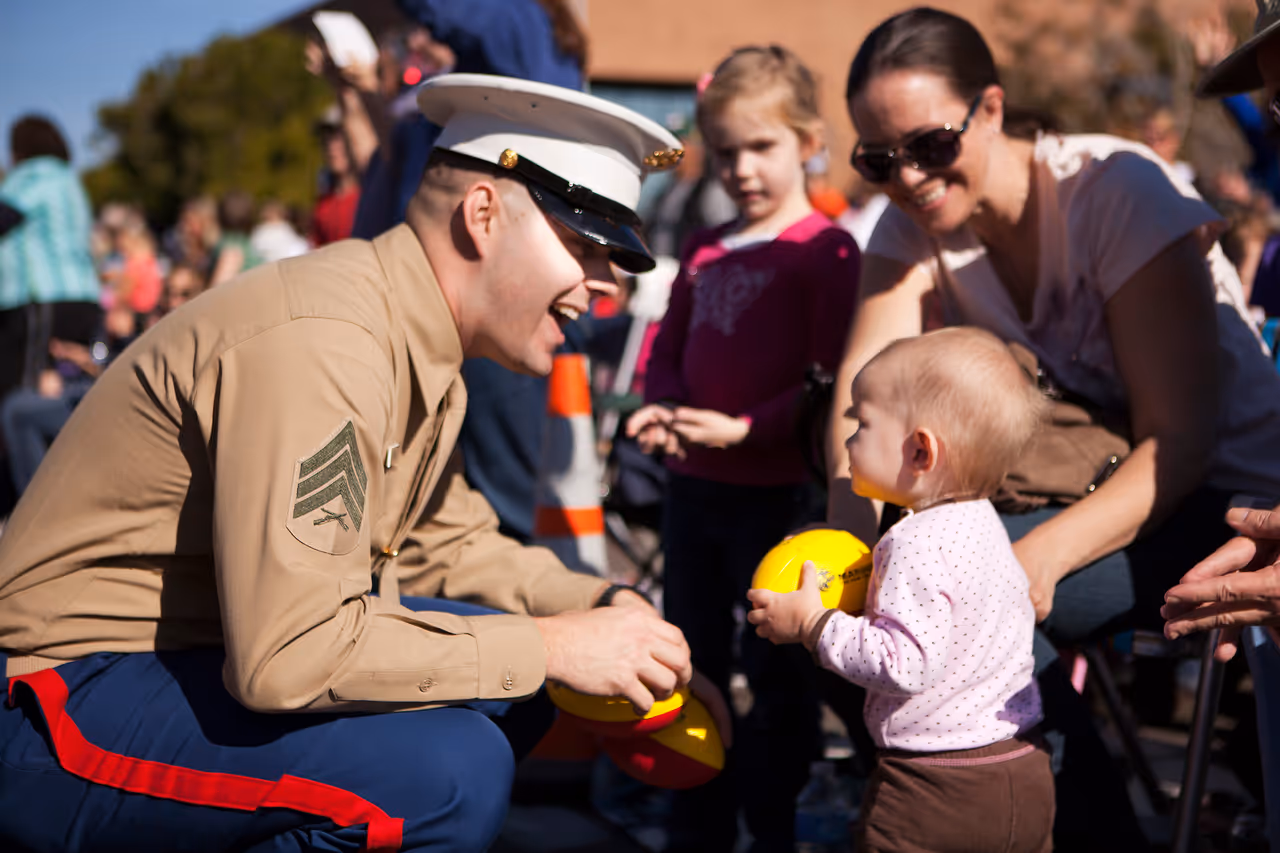 A Marine gives a football to a baby during the Fiesta Bowl Parade in Phoenix, Ariz., Dec.